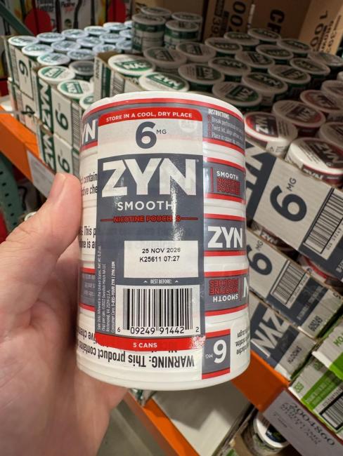 A circular package of "ZYN" branded illegal nicotine to be looking out for. With large white bolded letters noting the brand name ZYN, and mentions of a European product on the label. This product fits in your hand and is white with grey label and red lines. 